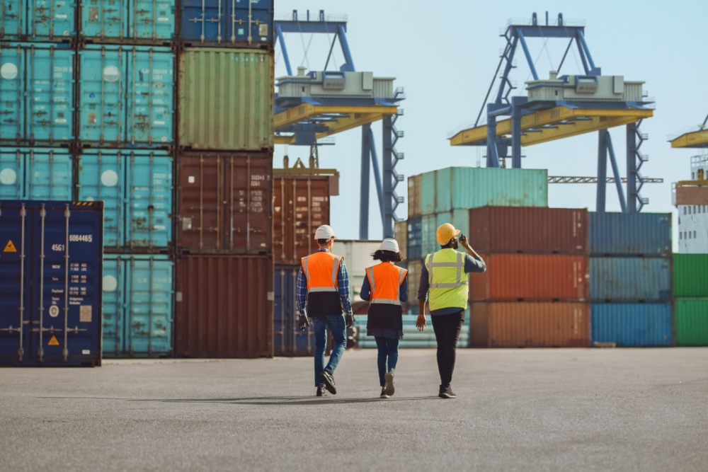 Workers walking through a shipping cargo container terminal depot