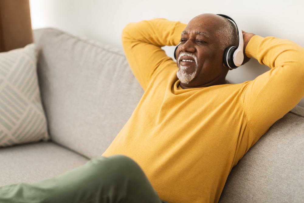 A man relaxing on a sofa with his hands behind his head.